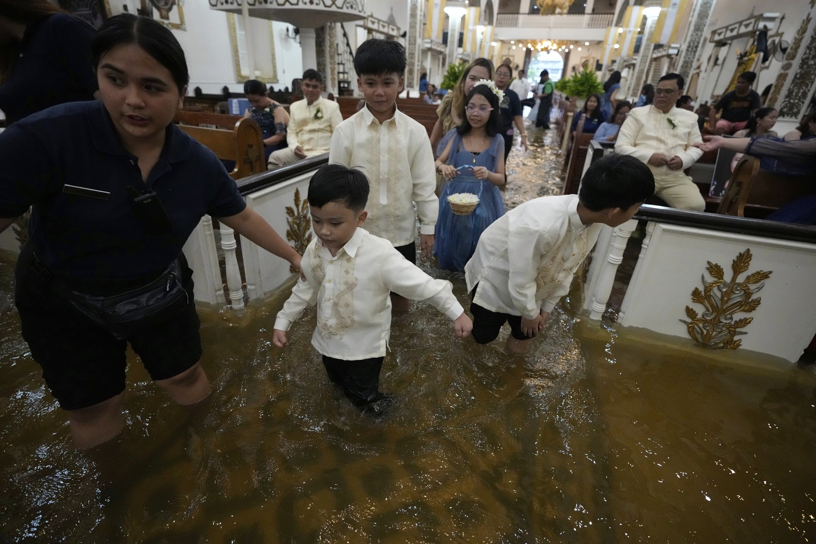 Wedding guests walk inside a flooded church.