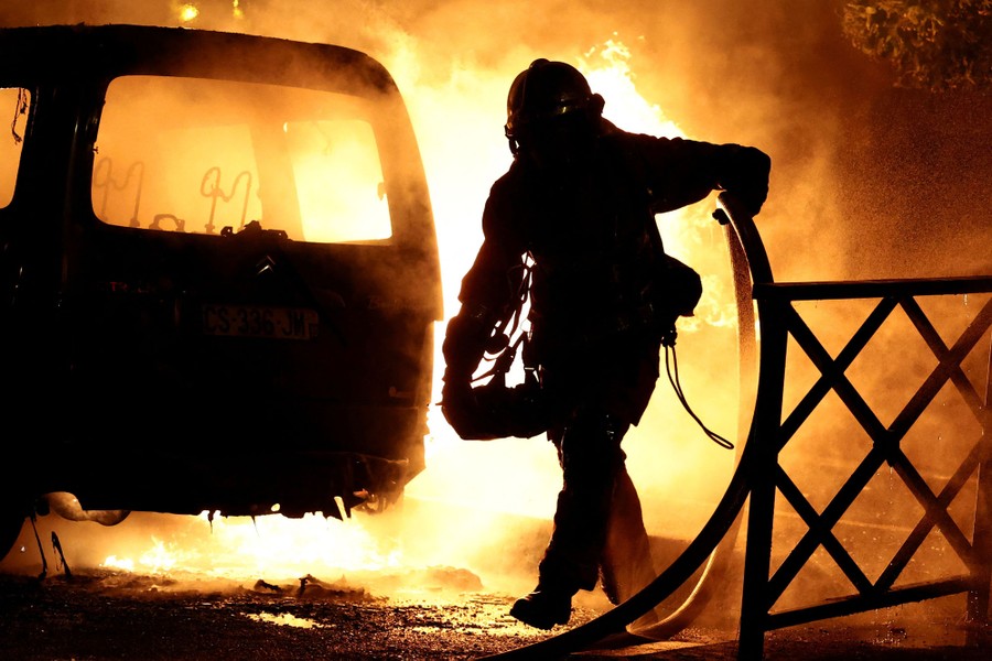 A firefighter works to extinguish burning vehicles.