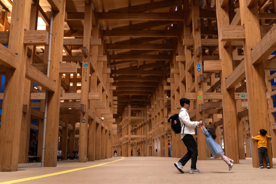 A family plays inside a cavernous structure made of many long wooden beams.