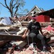 A woman sits on the wreckage of her home
