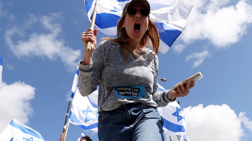 Low angle shot picture of woman holding Israeli flag and screaming.
