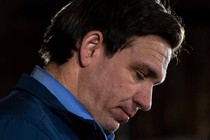 A close-up photo of Ron DeSantis's head and shoulders with his eyes cast downward