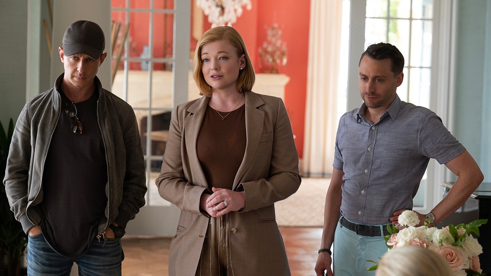 Three characters from HBO's "Succession" all dressed in "stealth wealth" clothing, including a several-hundred-dollar black wool baseball cap on one of them.
