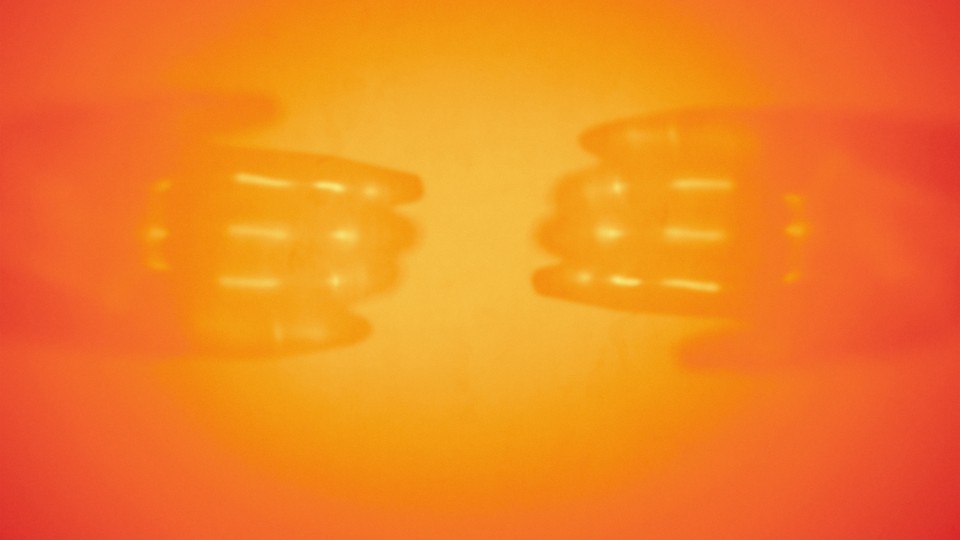 A burst of orange light with the faint outline of hands around the light burst