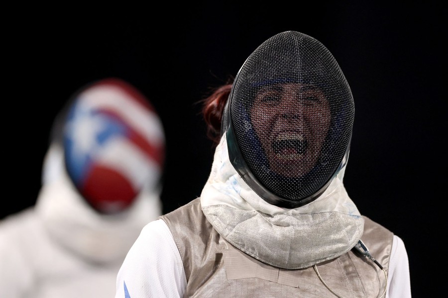 A fencer reacts, celebrating while still wearing their protective mask.