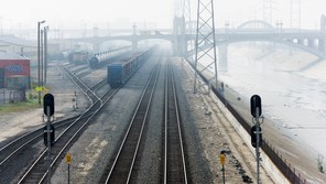 A photograph of cargo trains merging tracks in a foggy environment
