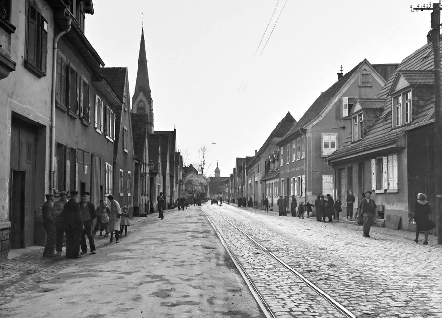People stand in groups in the street outside homes, in a German city, in 1945.