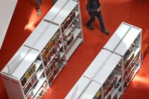 People walk between library shelves