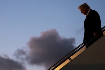 Color photograph of Trump walking down the stairs on Air Force One.