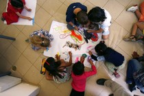 Preschoolers scribbling with markers and crayons on a large white paper