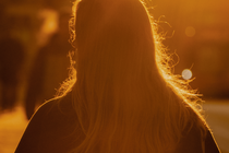 photo of long-haired woman facing away from camera and backlit by golden sunlight