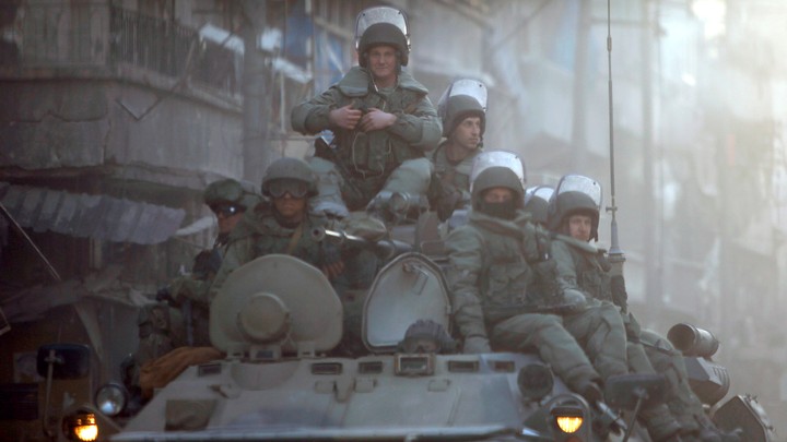 Heavily armed Russian soldiers ride atop an armored tank in Aleppo.