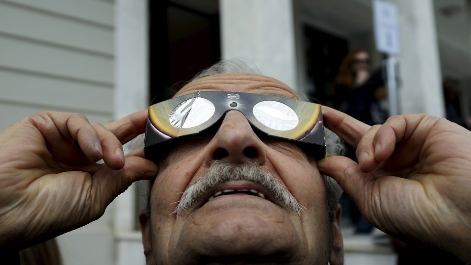 A man looks through eclipse glasses.