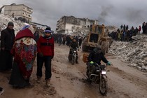 Photo showing Syrian civilians inspecting a destroyed residential building following a 7.8-magnitude earthquake