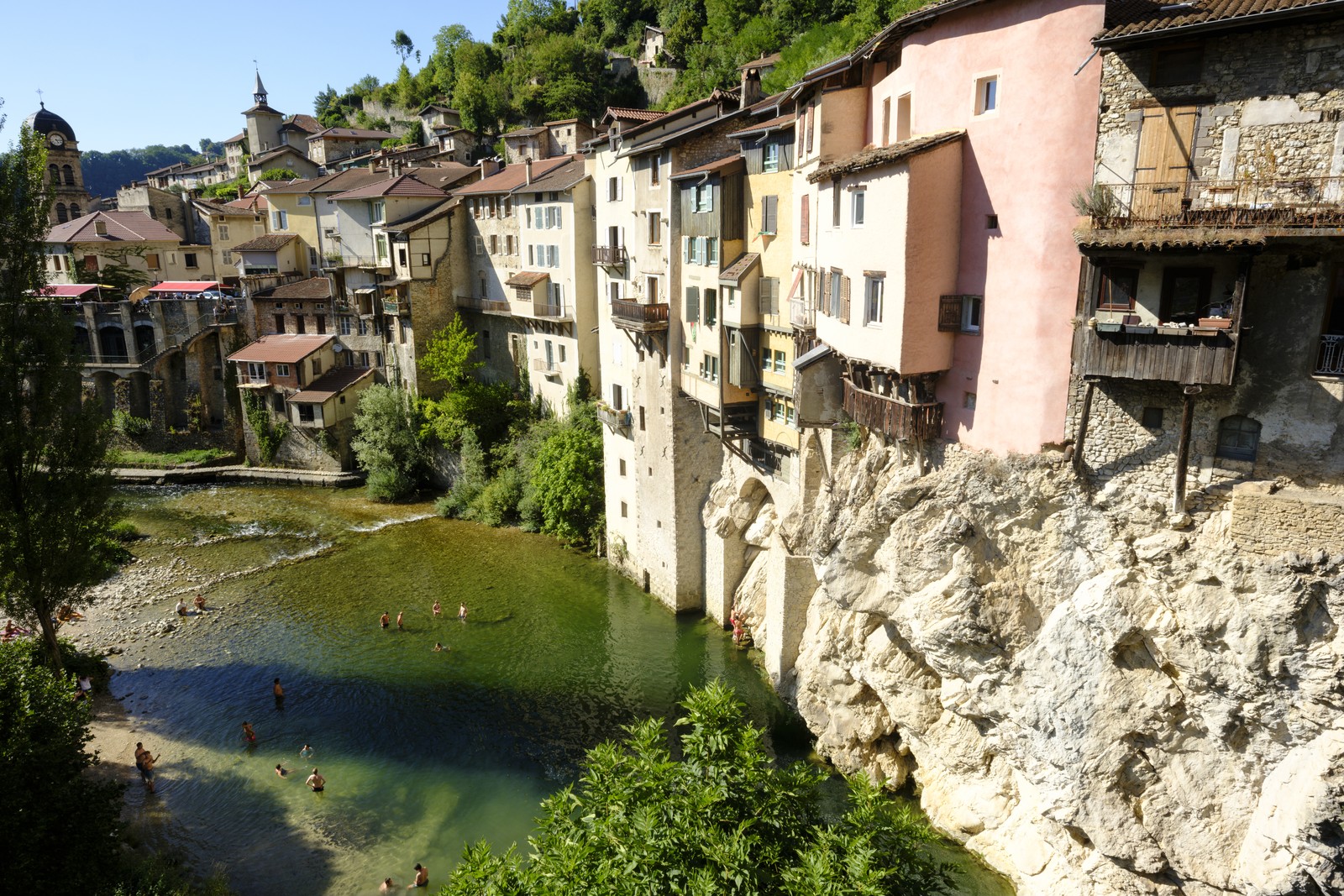 An overview of people swimming in a river beneath tall, medieval-style buildings