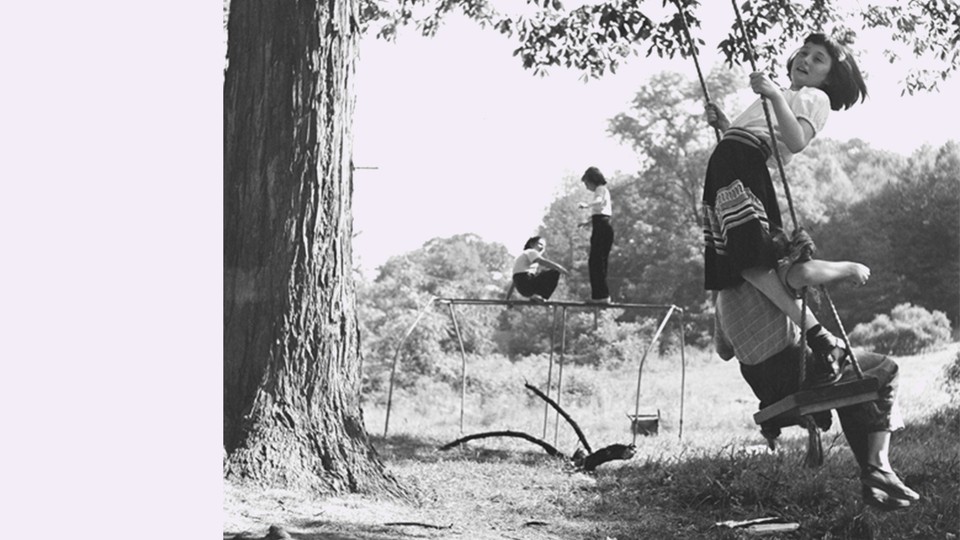 A black and white photo of girls playing outdoors in front of a light pink background