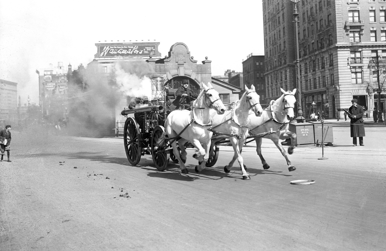 Onlookers watch as a horse-drawn fire engine is pulled down a city street in New York.
