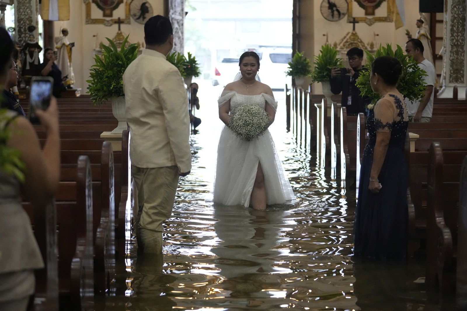 A bride walks down the aisle of a church, through foot-deep floodwater.