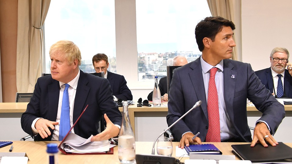 Boris Johnson and Justin Trudeau sit alongside each other at a table.