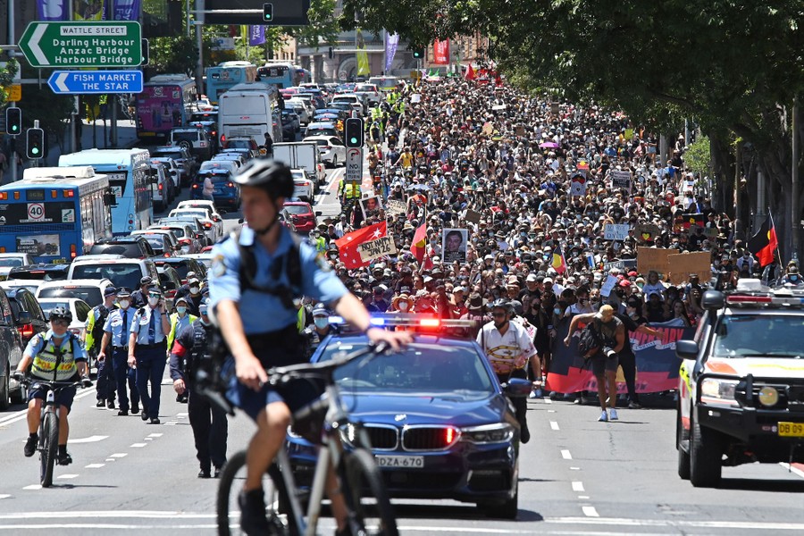 A large crowd of protesters marches down a city street.