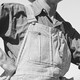A black-and-white photograph of a man in striped overalls