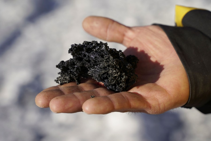 A person holds a small, rough, chunk of volcanic rock.