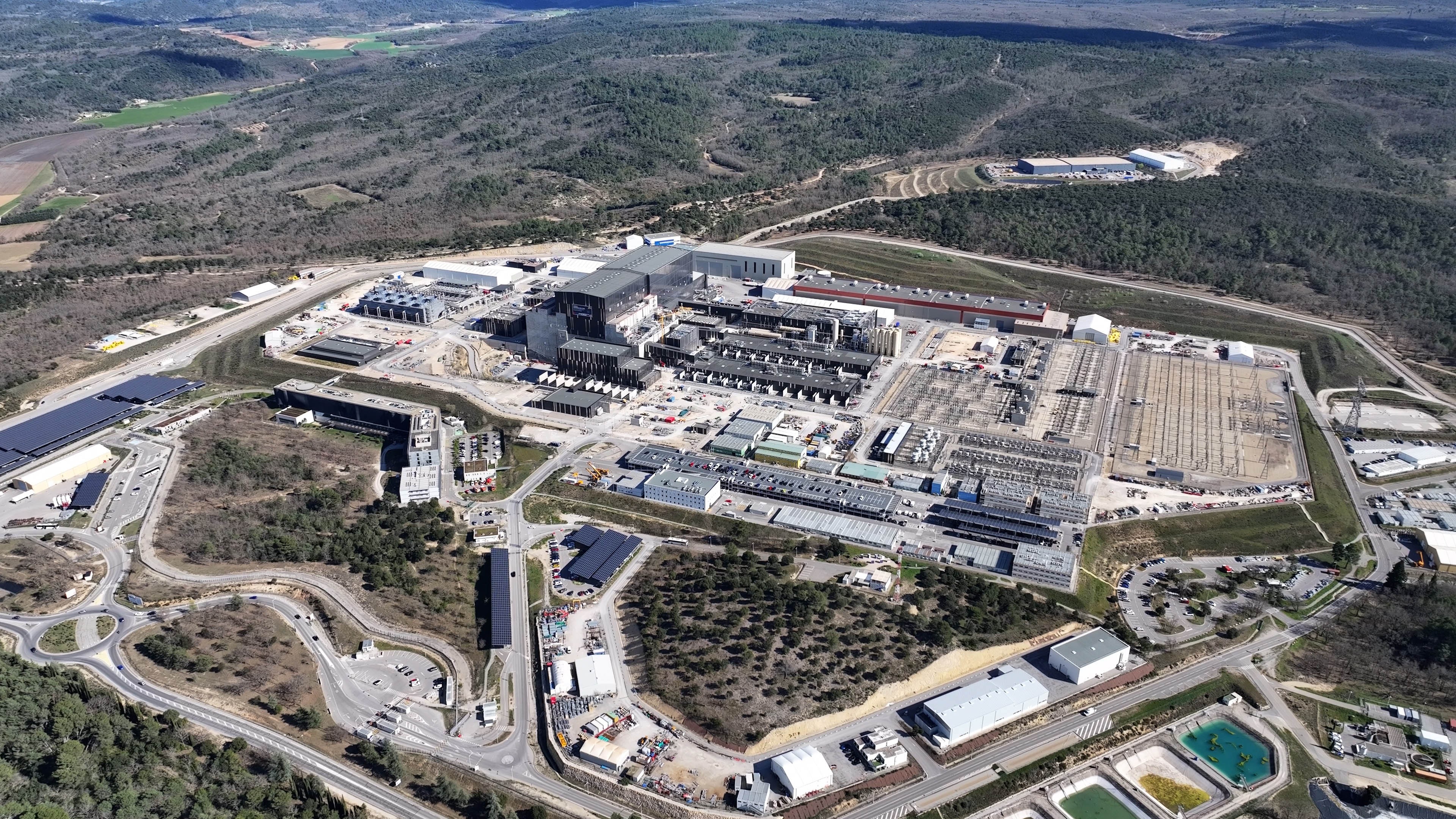 An aerial view of a sprawling complex of large and small buildings and electrical infrastructure