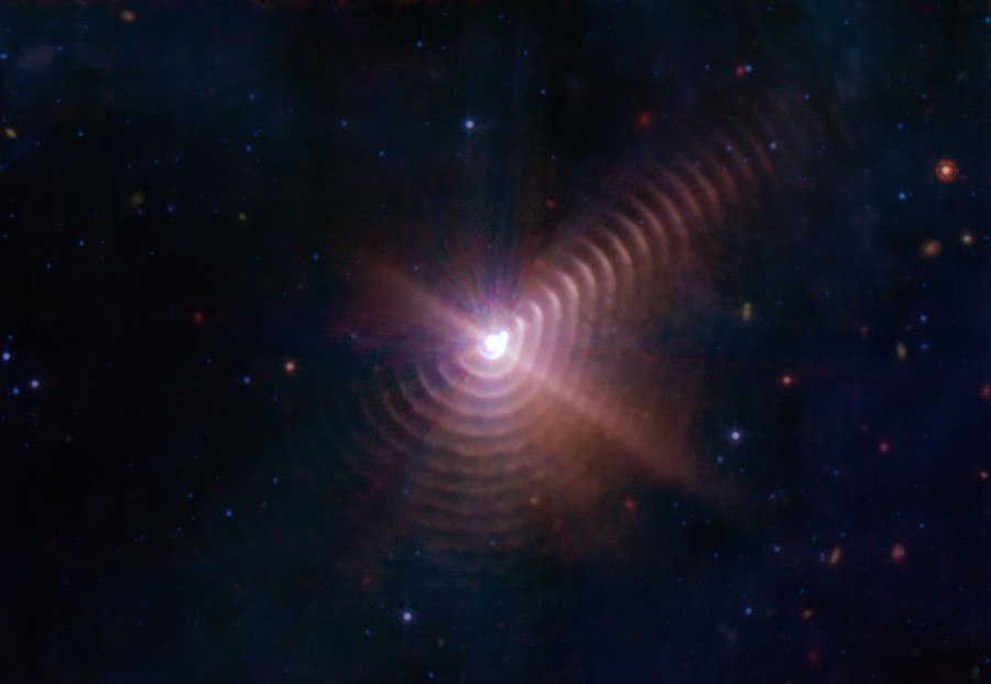 A set of concentric circles in outer space, a phenomenon created by two stars orbiting closely, throwing off gas and dust