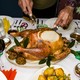 A man carves a Thanksgiving turkey on a dinner table