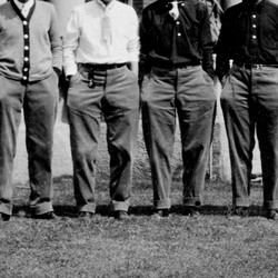 Fraternity men stand with their hands in their pockets, with their heads out of frame.