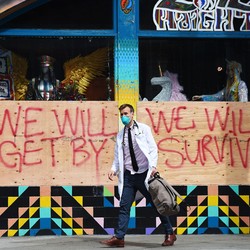 A doctor with the Haight Ashbury Free Clinic walks by a supportive sign in San Francisco.