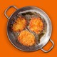 Three latkes frying in a pan