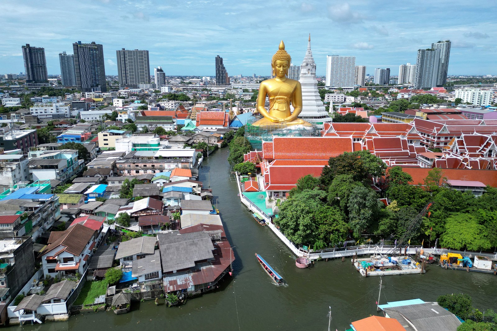 An aerial view of a neighborhood dominated by a gigantic golden statue of a seated Buddha.