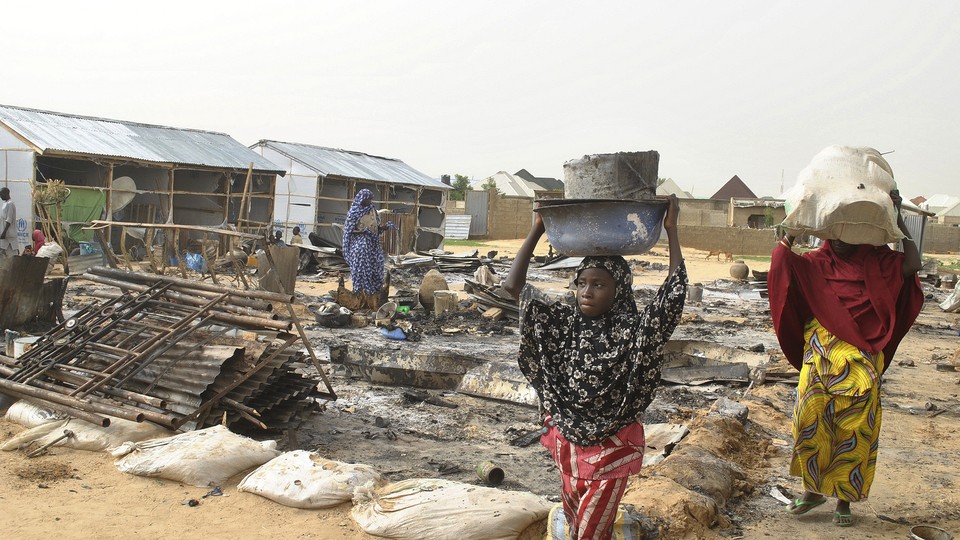 People walk through the debris following an explosion in Maiduguri in early June.