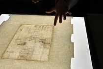 A hand points to a light box with a Da Vinci drawing