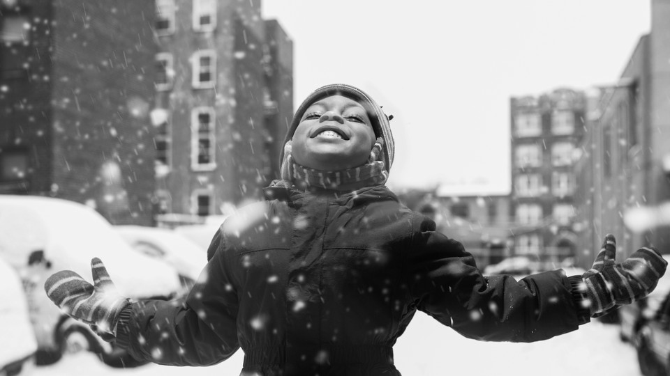 A girl lifts her face to the sky as snow falls.