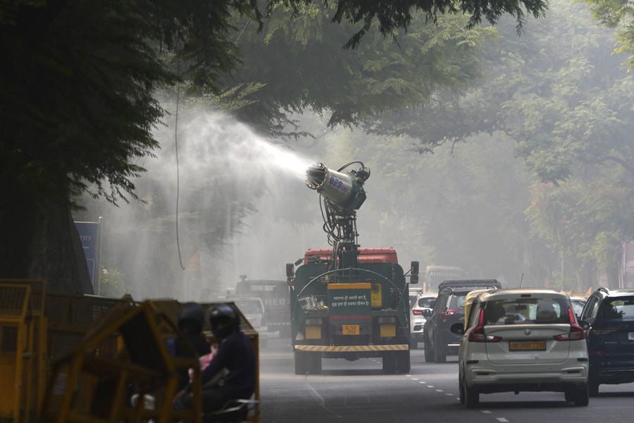 A vehicle sprays mist from a cannon as it drives through traffic.