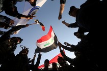 Circle of Iraqi soldiers celebrate as they waive an Iraqi flag.