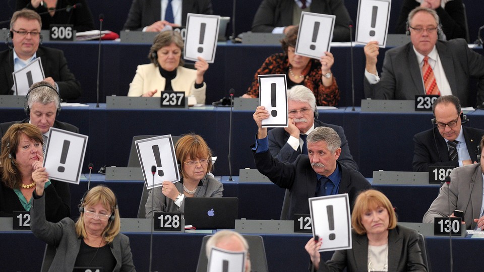 Men and women hold placards bearing an exclamation mark