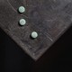 A color photograph of a black, scuffed service with three small, teal-colored pills on top.
