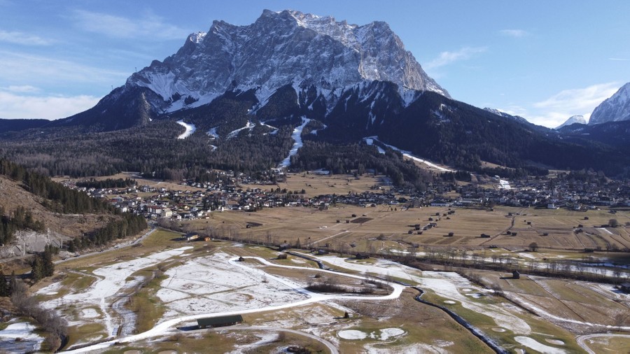 A view of a large mountain rising above a valley, with a ski resort at its base.