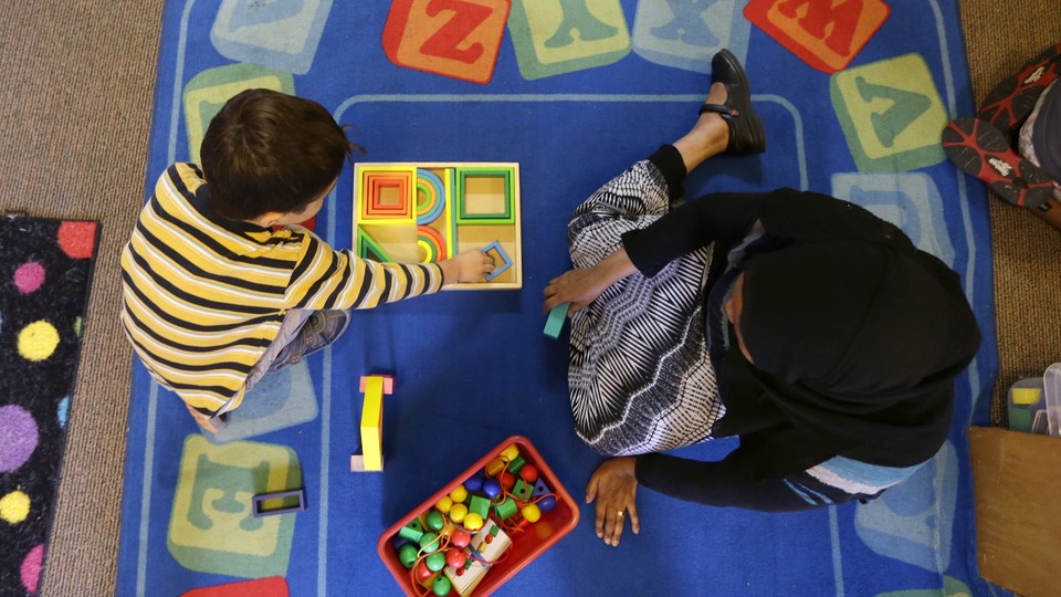 An overhead shot of a child playing with blocks on a blue carpet with an adult.