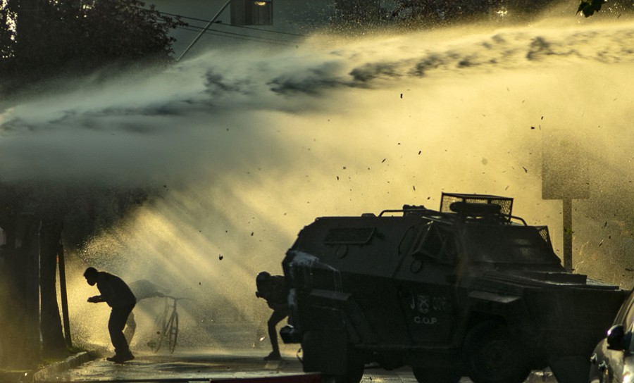 Protesters duck as a water cannon is sprayed over their heads.