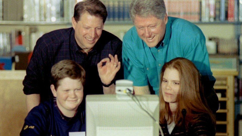 Four people staring at an old computer 