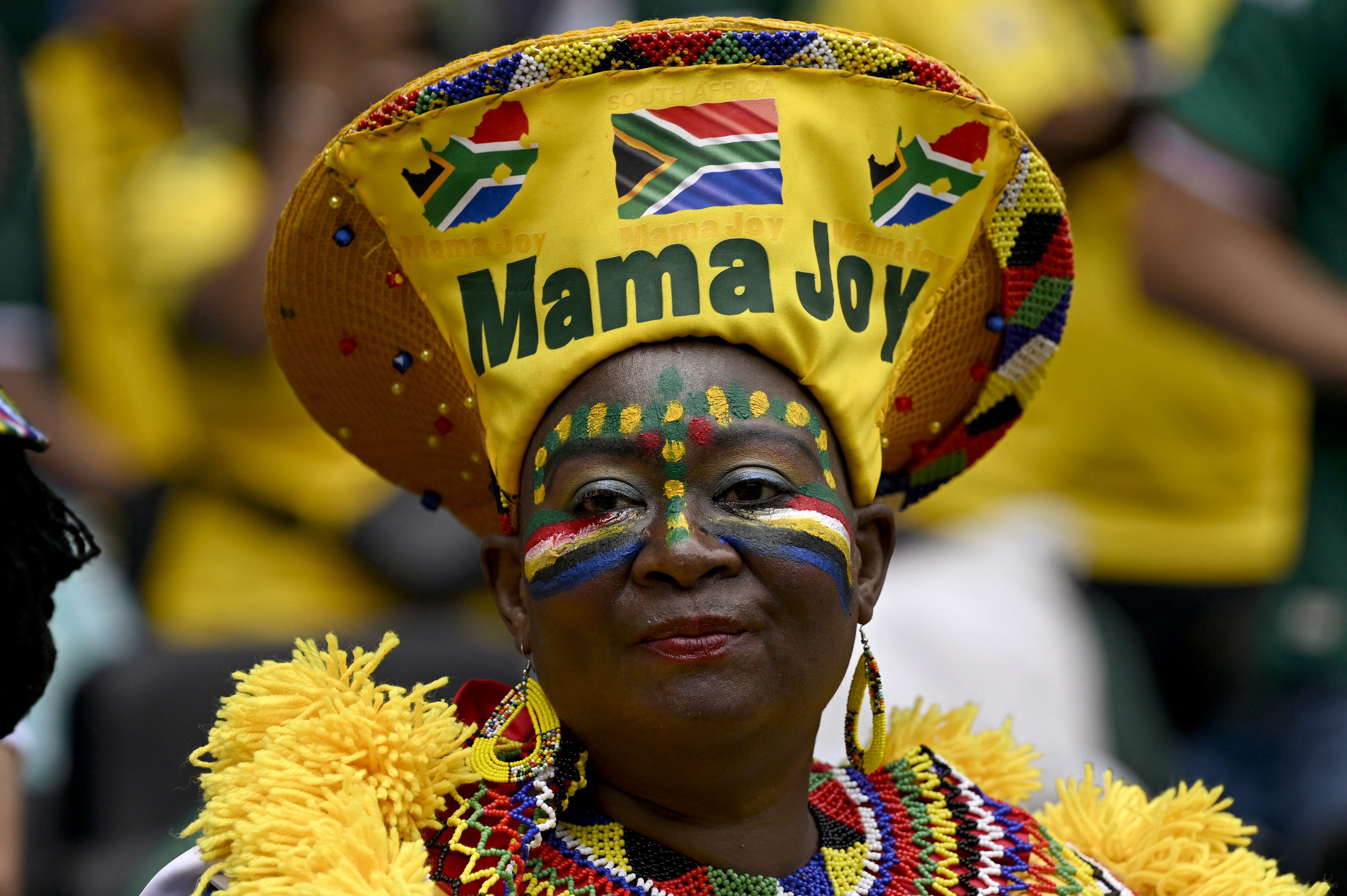 A fan of Team South Africa wears a costume including a tall hat that reads 'Mama Joy'.