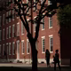 Photograph of pedestrians passing by a red brick dormitory in Harvard Yard at Harvard University