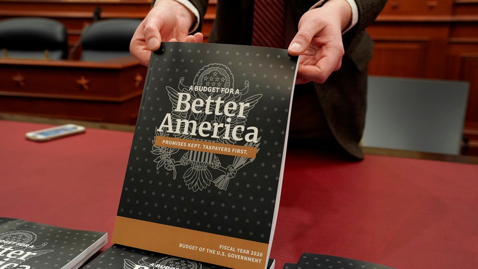 An aide holds up a copy of Volume 1 of President Donald Trump's budget for fiscal year 2020.