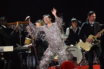 Harry Styles performing in a silver tassled jumpsuit