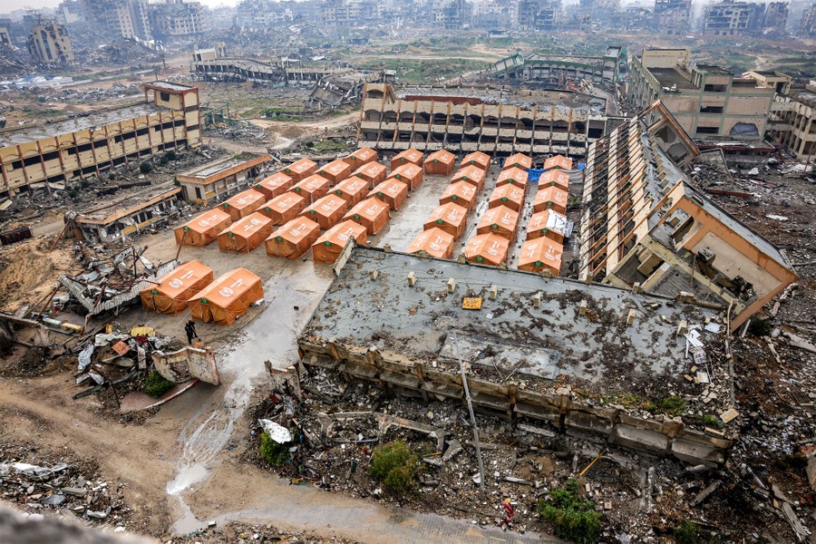 A refugee tent city, set up in a schoolyard, among many damaged and destroyed buildings in Gaza