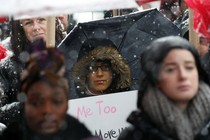 A woman holds a "Me Too" sign. 